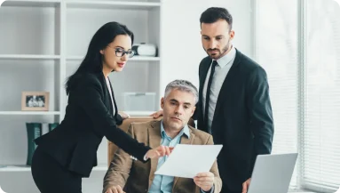 Three professionals reviewing a document together